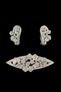 Vertical front view of 1950s vintage Whiting and Davis pewter floral brooch and clip-on earrings jewelry set.