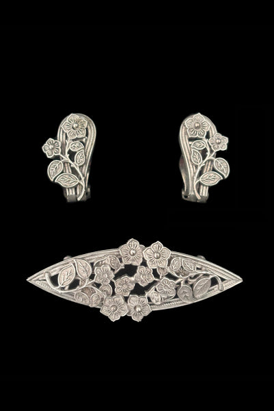 Vertical front view of 1950s vintage Whiting and Davis pewter floral brooch and clip-on earrings jewelry set.