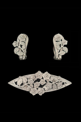 Vertical front view of 1950s vintage Whiting and Davis pewter floral brooch and clip-on earrings jewelry set.
