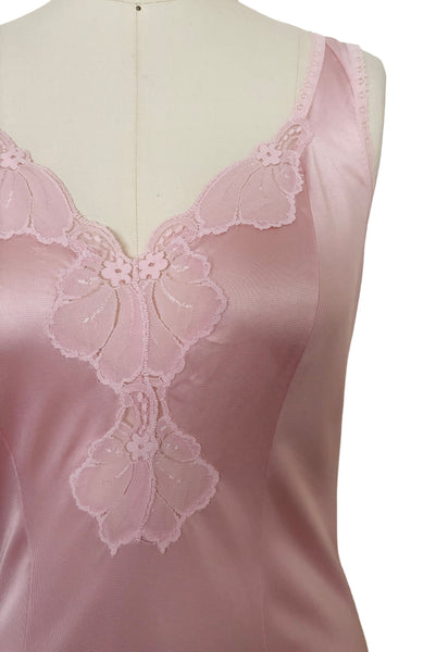Detail view of 1970s vintage blush pink nylon tricot floral lace trimmed nightgown by Maidenform, size extra small to small. Showing the curved V-neckline, and princess seams.