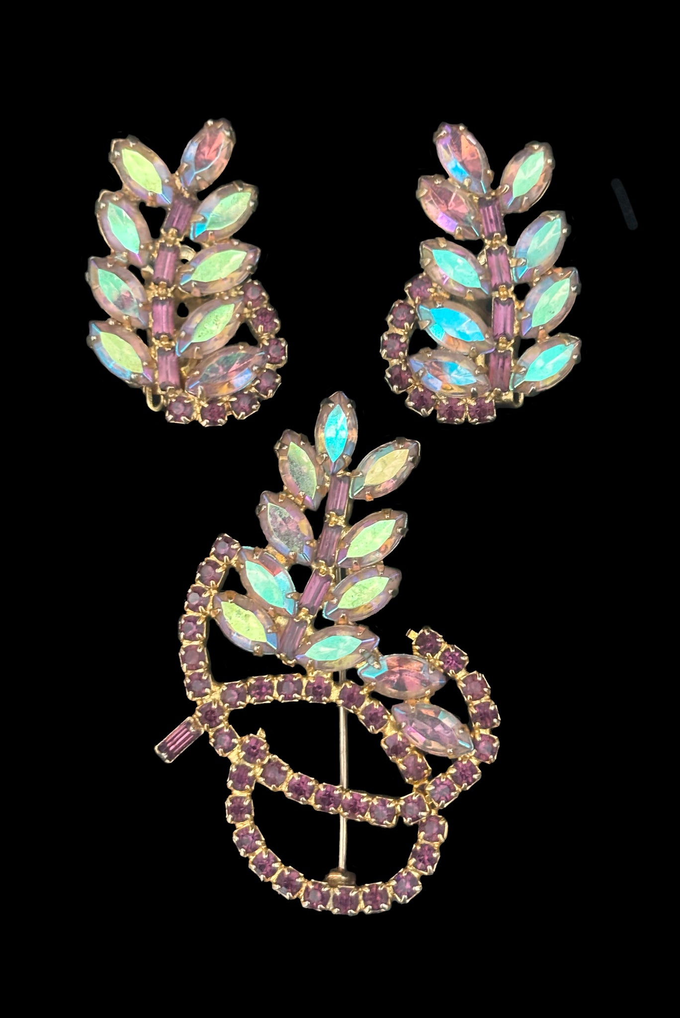 Vertical front view of 1950s vintage iridescent and amethyst purple rhinestone leaf brooch and clip-on earring set.