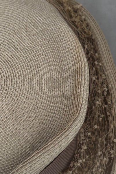 Detail view of 1940s vintage taupe straw riding style tilt topper hat with matching petersham ribbon and veiling trim, by Marche. Showing a light mark on the straw.