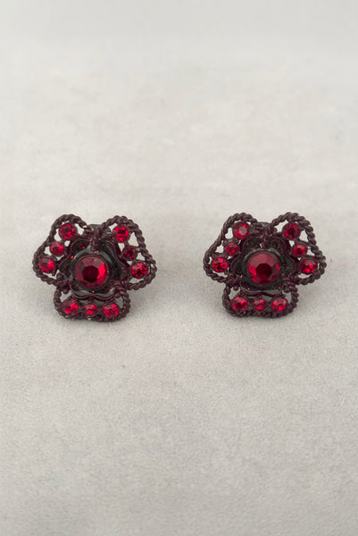 Vertical front view of 1960s vintage brown painted metal three leaf clover red rhinestone clip-on earrings.