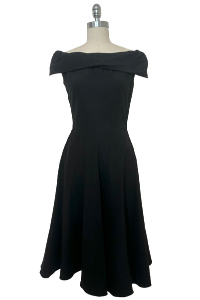 Front view of 1950s vintage folded collar off the shoulder black dress with full skirt, size extra small to small.