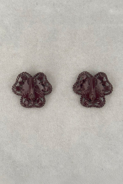 Vertical back view of 1960s vintage brown painted metal three leaf clover red rhinestone clip-on earrings.