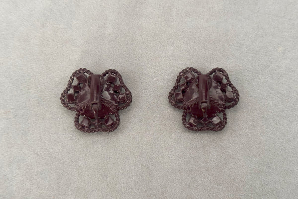 Horizontal back view of 1960s vintage brown painted metal three leaf clover red rhinestone clip-on earrings.