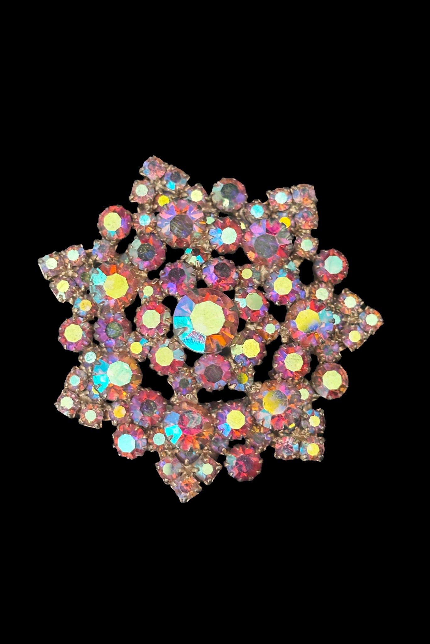 Vertical front view of 1950s vintage large round iridescent pink rhinestone snowflake statement brooch.