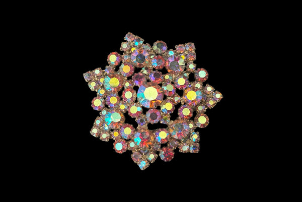 Horizontal front view of 1950s vintage large round iridescent pink rhinestone snowflake statement brooch.