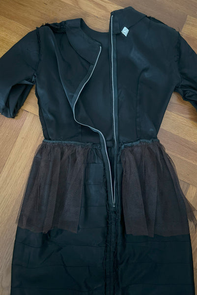 Interior detail view of 1960s vintage crew neck, 3/4 sleeve, bow trimmed black faille cocktail dress, with tiered skirt, size small to medium. Showing the tulle at the hips, and metal zipper.
