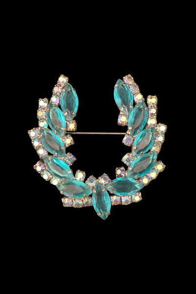 Vertical front view 1950s vintage iridescent blue round  and aqua marquise rhinestone and silver tone metal horseshoe brooch.