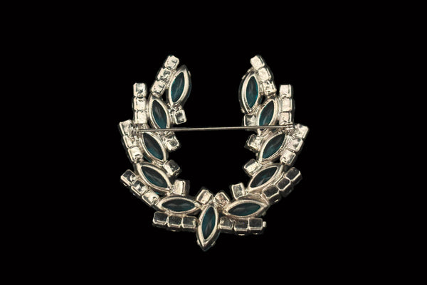 Horizontal back view 1950s vintage iridescent blue round  and aqua marquise rhinestone and silver tone metal horseshoe brooch.