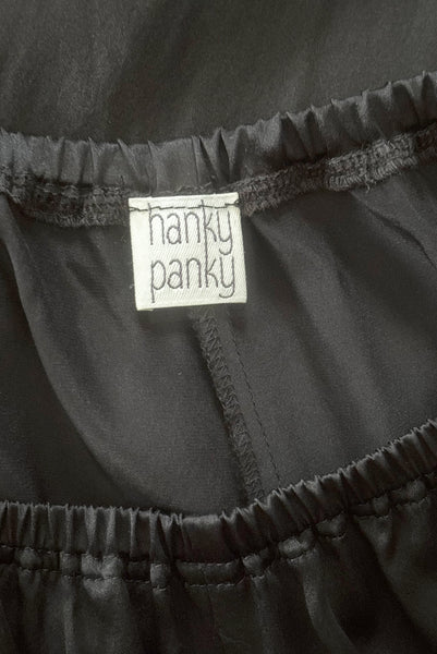 Interior detail view of 2000s y2k vintage black silk charmeuse satin elastic waist, high rise, wide leg pajama loungewear pants, by Hanky Panky, size medium to large. New without tags. Showing the Hanky Panky label.