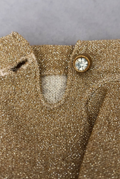 Detail view of 1950s vintage wrist length stretchy metallic gold nylon mylar gloves with clear rhinestone buttons. Showing a close-up of the wrist with rhinestone button and button hole.