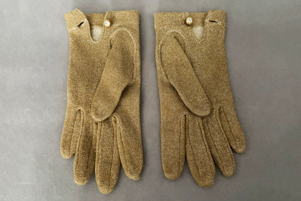 Horizontal back view of 1950s vintage wrist length stretchy metallic gold nylon mylar gloves with clear rhinestone buttons.