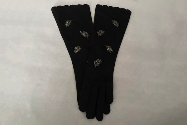Horizontal pair view of 1950s vintage mid length black Reindoe Nylon scalloped cuff gloves with gold embroidery and silver beaded leaves by Van Raalte, size 7.