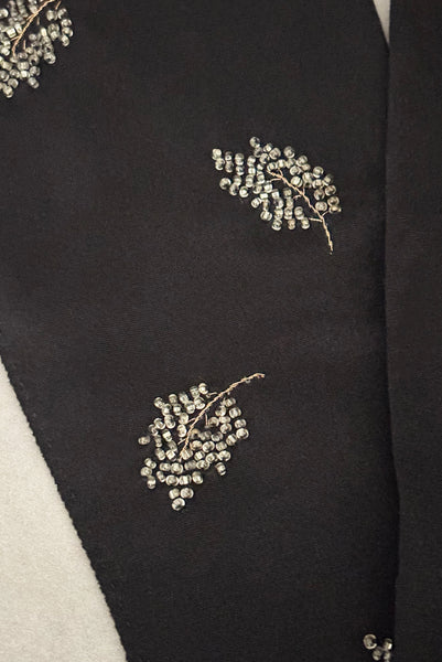 Detail view of 1950s vintage mid length black Reindoe Nylon scalloped cuff gloves with gold embroidery and silver beaded leaves by Van Raalte, size 7. Showing a close-up of the leaf embellishments.