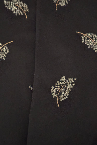 Detail view of 1950s vintage mid length black Reindoe Nylon scalloped cuff gloves with gold embroidery and silver beaded leaves by Van Raalte, size 7. Showing a close-up of the leaf embellishments.