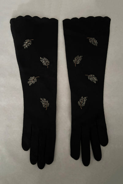 Vertical front view of 1950s vintage mid length black Reindoe Nylon scalloped cuff gloves with gold embroidery and silver beaded leaves by Van Raalte, size 7.