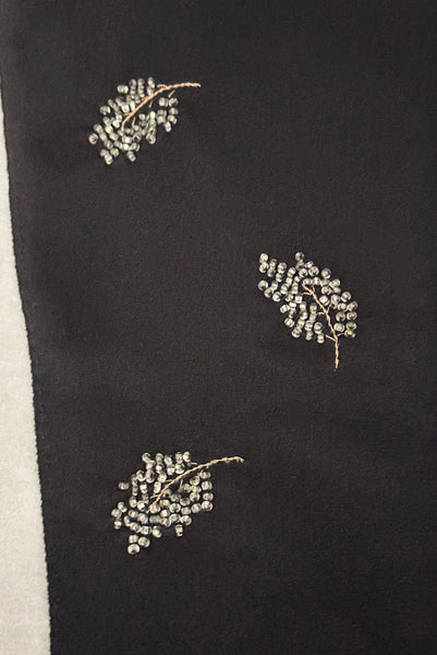 Detail view of 1950s vintage mid length black Reindoe Nylon scalloped cuff gloves with gold embroidery and silver beaded leaves by Van Raalte, size 7. Showing a close-up of the leaf embellishments.