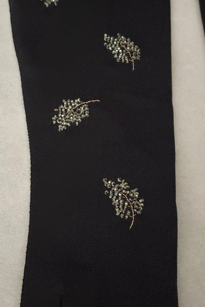 Detail view of 1950s vintage mid length black Reindoe Nylon scalloped cuff gloves with gold embroidery and silver beaded leaves by Van Raalte, size 7. Showing a close-up of the leaf embellishments.