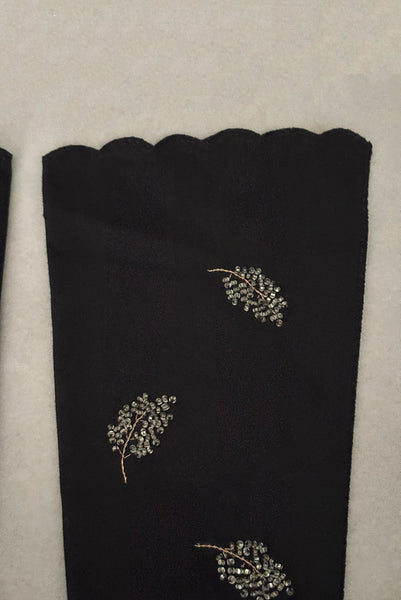 Detail view of 1950s vintage mid length black Reindoe Nylon scalloped cuff gloves with gold embroidery and silver beaded leaves by Van Raalte, size 7. Showing a close-up of the leaf embellishments and the scalloped cuff.