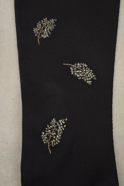 Detail view of 1950s vintage mid length black Reindoe Nylon scalloped cuff gloves with gold embroidery and silver beaded leaves by Van Raalte, size 7. Showing a close-up of the leaf embellishments.