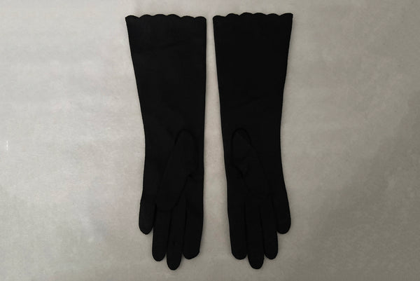 Horizontal back view of 1950s vintage mid length black Reindoe Nylon scalloped cuff gloves with gold embroidery and silver beaded leaves by Van Raalte, size 7.