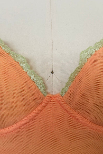 Detail view of 2000s y2k vintage, as is, new with tags creamsicle orange mesh and green lace underwire bustier with laced back by Cosabella, size extra small to small. Showing the cups with underwires trimmed in green lace.