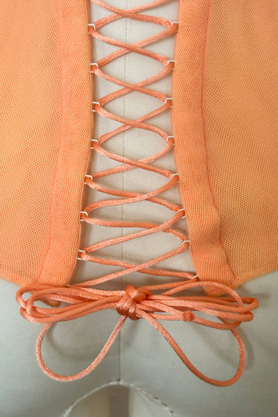 Detail view of 2000s y2k vintage, as is, new with tags creamsicle orange mesh and green lace underwire bustier with laced back by Cosabella, size extra small to small. Showing the metal eyes with satin cording on the laced up back.