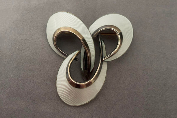 Horizontal front view of 1950s vintage Hans Myhre 925 sterling silver and white guilloche enamel brooch. Made in Norway.