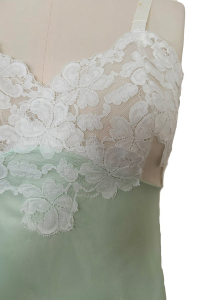 Bodice front detail view of 1960s vintage pale mint green and white lace mini full slip by Philmade, medium to large. Showing the floral pattern white lace and one of the spot on the strap.