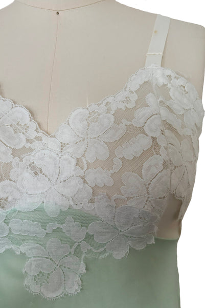 Bodice front detail view of 1960s vintage pale mint green and white lace mini full slip by Philmade, medium to large. Showing the floral pattern white lace and one of the spot on the strap.