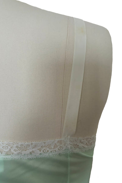 Back detail view of 1960s vintage pale mint green and white lace mini full slip by Philmade, medium to large. Showing the floral pattern white lace and one of the spot on the strap.