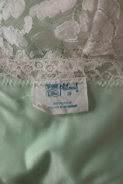 Interior detail view of 1960s vintage pale mint green and white lace mini full slip by Philmade, medium to large. Showing the label and tag.