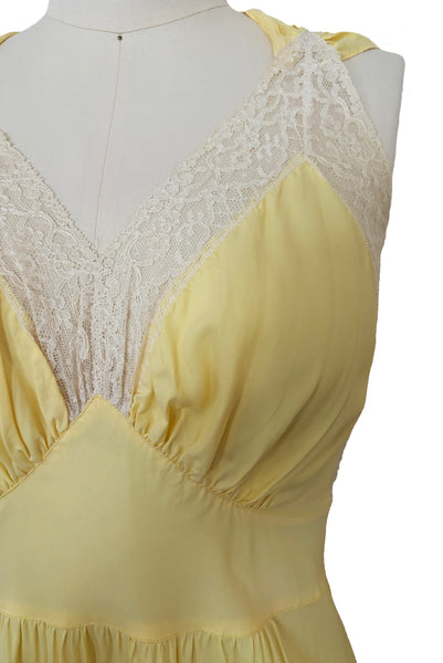 Bodice detail view of vintage 1940s yellow bias cut rayon and cream lace sweetheart neckline nightgown, medium to large. Showing the ivory lace trimmed neckline, gathered bust, and pointed midriff band.