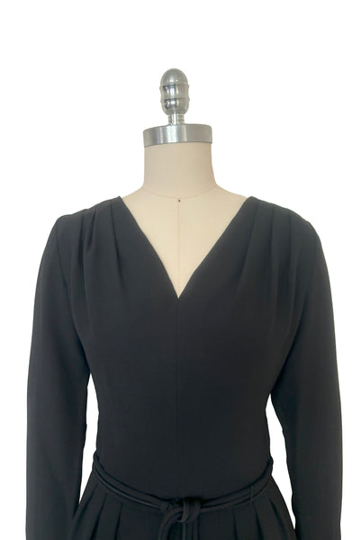 Bodice front view of 1950s vintage long sleeve, V-neck black crepe wiggle dress with triple stand self tie belt, by R&K Originals, small to medium. Showing the pleated shoulders.