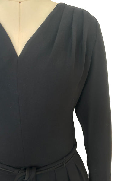 Bodice front detail view of 1950s vintage long sleeve, V-neck black crepe wiggle dress with triple stand self tie belt, by R&K Originals, small to medium. Showing the pleated shoulders.