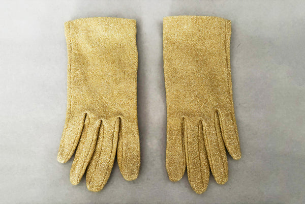 Horizontal front view of 1950s vintage wrist length stretchy metallic gold nylon mylar gloves with clear rhinestone buttons.