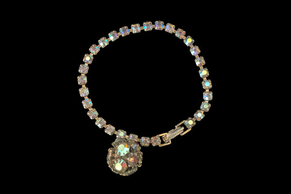 Horizontal front view of 1950s vintage single line iridescent round rhinestone gold tone bracelet with matching rhinestone ball charm by Weiss.