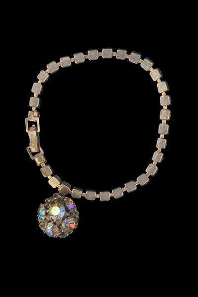 Vertical back view of 1950s vintage single line iridescent round rhinestone gold tone bracelet with matching rhinestone ball charm by Weiss.