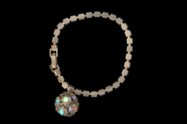 Horizontal back view of 1950s vintage single line iridescent round rhinestone gold tone bracelet with matching rhinestone ball charm by Weiss.