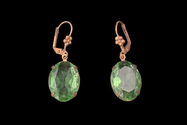 Horizontal flat view of 2010s vintage faceted glass oval peridot green rhinestone and brass lever back drop earrings made from vintage components.