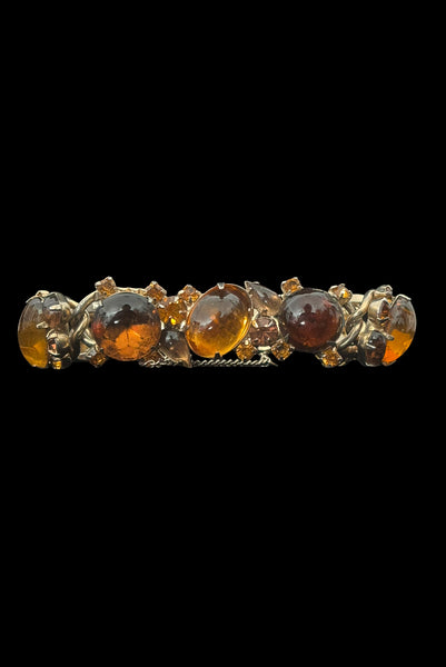 Vertical front view of 1950s vintage Weiss autumnal orange, brown, and iridescent rhinestone and foil backed glass cabochon gold tone bracelet.