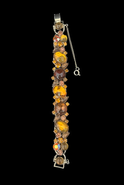 Vertical front view of 1950s vintage Weiss autumnal orange, brown, and iridescent rhinestone and foil backed glass cabochon gold tone bracelet.