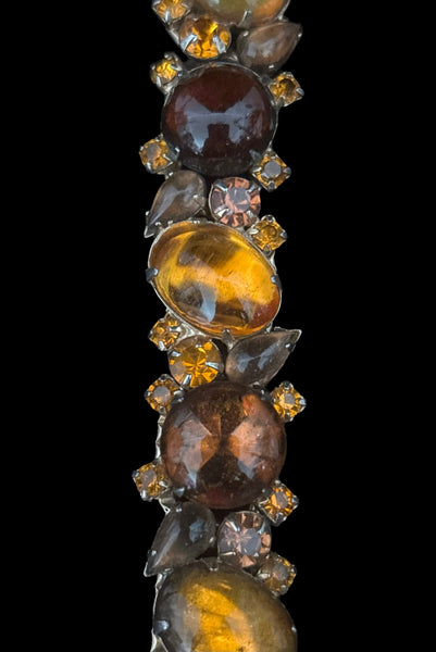 Detail view of 1950s vintage Weiss autumnal orange, brown, and iridescent rhinestone and foil backed glass cabochon gold tone bracelet. Showing some dark spots in the glass cabochons.