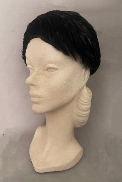 Vertical 3/4 view of 1960s vintage jet black feather and felt casque hat. On a mannequin head.
