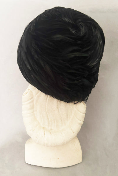 Vertical back view of 1960s vintage jet black feather and felt casque hat. On a mannequin head.