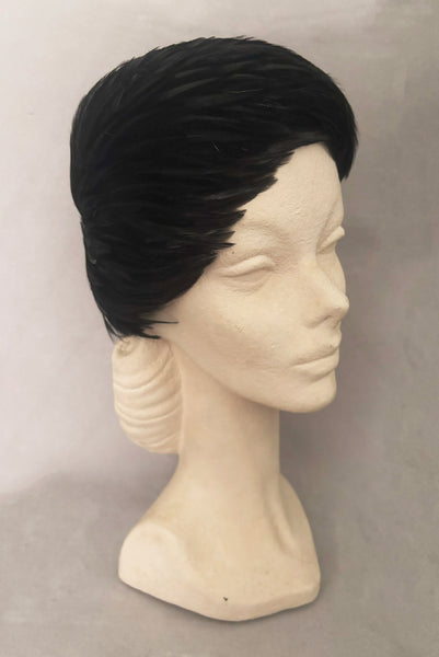 Vertical 3/4 view of 1960s vintage jet black feather and felt casque hat. On a mannequin head.