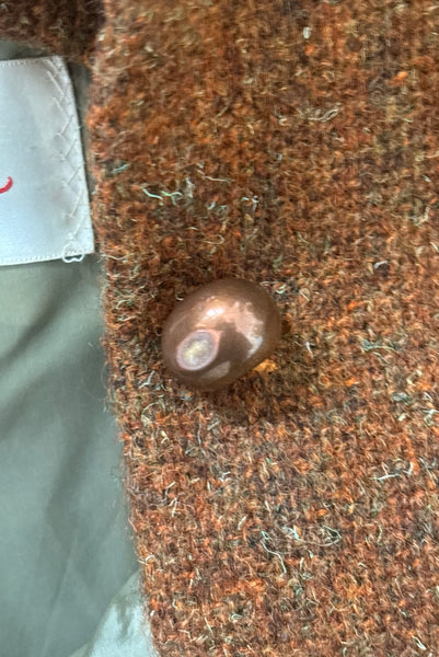 Detail view of 1960s vintage rust brown wool, three copper metal button, long sleeve jacket by Pauline Trigère for Bergdorf Goodman, size medium to large. Showing a dent in one of the copper colored buttons.