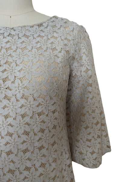 Detail view of 1960s vintage white and beige floral lace shift dress, size medium to large. Showing a close-up of the beige and white corded lace and shallow scoop neckline.